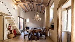 Un espace repas avec une table ronde et des chaises, un lustre et un escalier menant à un autre niveau.