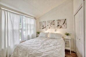 Relax in a serene bedroom with a large bed, sheer curtains, and framed artworks.