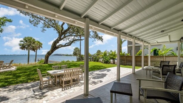 A covered outdoor patio with tables and chairs, a view of the water, and a large tree. - Stunning River Views - Historic 3br Walk Dntn (Melbourne)