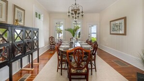 A dining room with a long table, chairs, a chandelier, and framed artwork on the walls. - Stunning River Views - Historic 3br Walk Dntn (Melbourne)