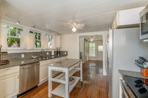 A kitchen with granite countertops, stainless steel appliances, and a ceiling fan.