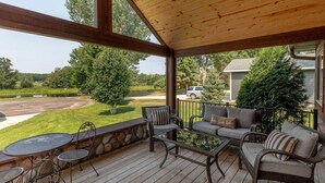 Une terrasse extérieure couverte, aménagée avec un canapé, des fauteuils et une table.