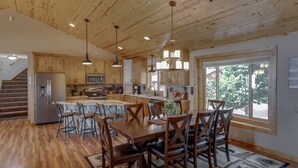 A spacious kitchen with wooden cabinets, a central island, and bar stools. - 2 Docks 2 Shores- Ramp, Water Toys, Game Room! (Garrison)