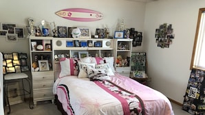A bedroom with a bed, a desk, and shelves with trophies and photos. - Spacious home, large deck with beautiful views in the heart of the Black Hills  (Rapid City)