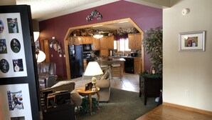 A living room with a fireplace, a dining area, and a kitchen with wooden cabinets. - Spacious home, large deck with beautiful views in the heart of the Black Hills  (Rapid City)