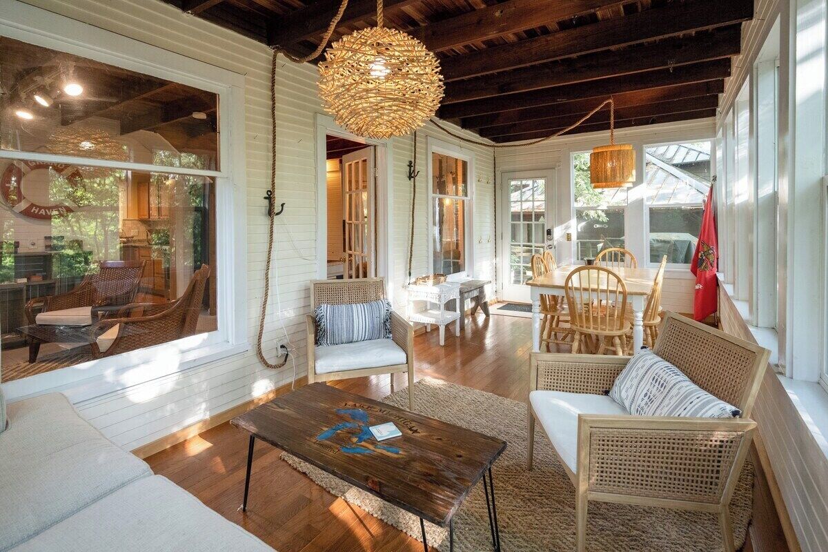 A spacious living area with wicker furniture, a wooden coffee table, and a hanging light fixture.