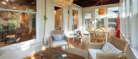 A spacious living area with wicker furniture, a wooden coffee table, and a hanging light fixture.