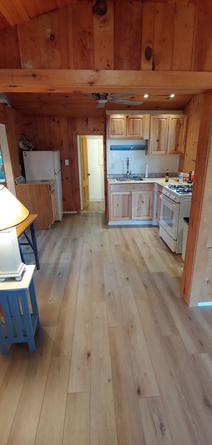 Kitchen features a central island, sink, and stove, with light-colored cabinets and a countertop.