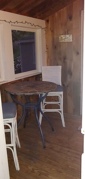 Enjoy a view of lush greenery from the room's window, which also features a bar and a table with two chairs.