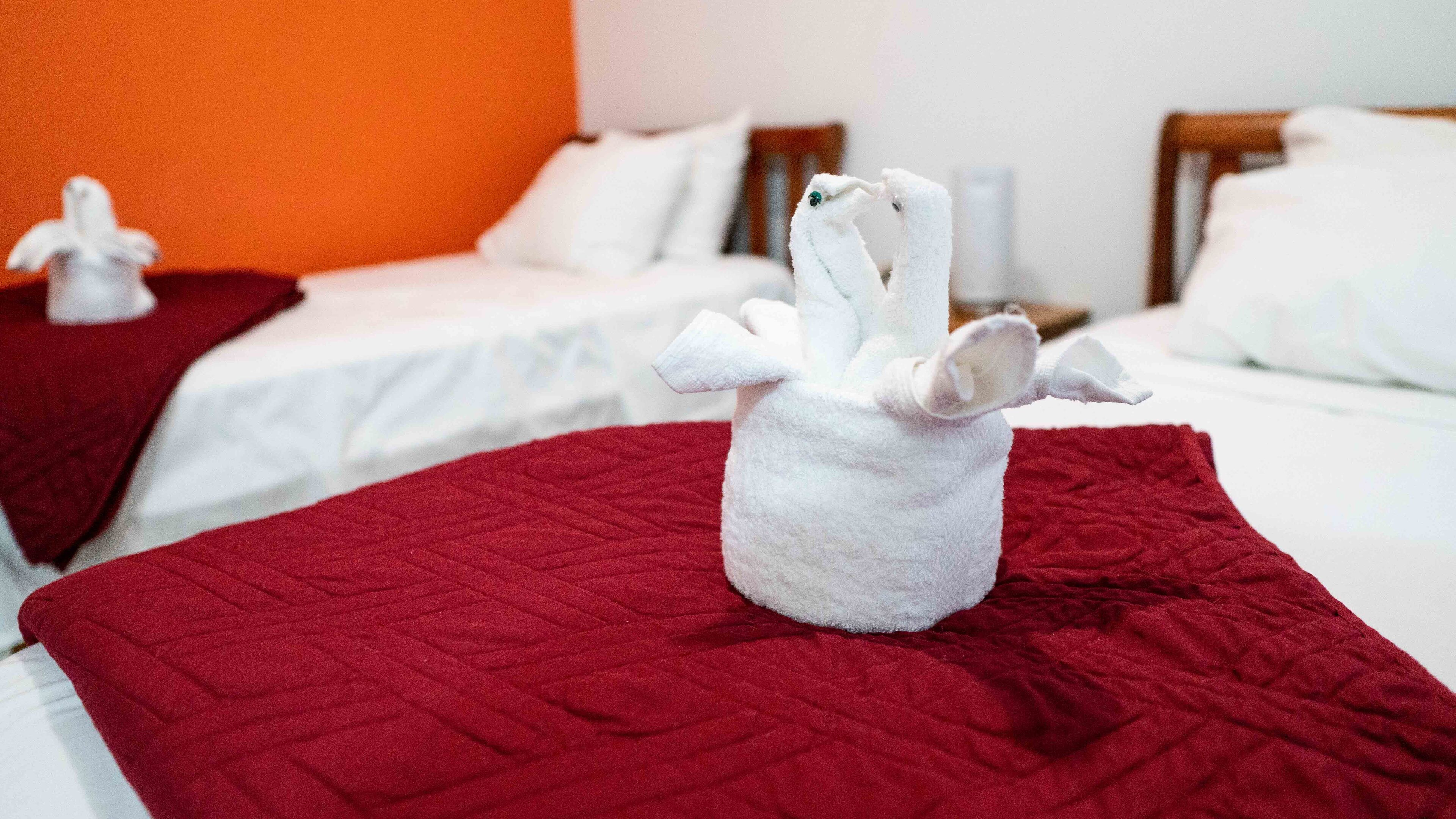 A hotel room with two beds, each with a red quilted bedspread and white pillows.