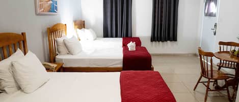 A hotel room with two beds, a dining table, and a chair.