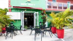 A Mini Mart with a green facade, outdoor seating area with black chairs and tables, and potted plants. - The Paradise Inn (Philipsburg)