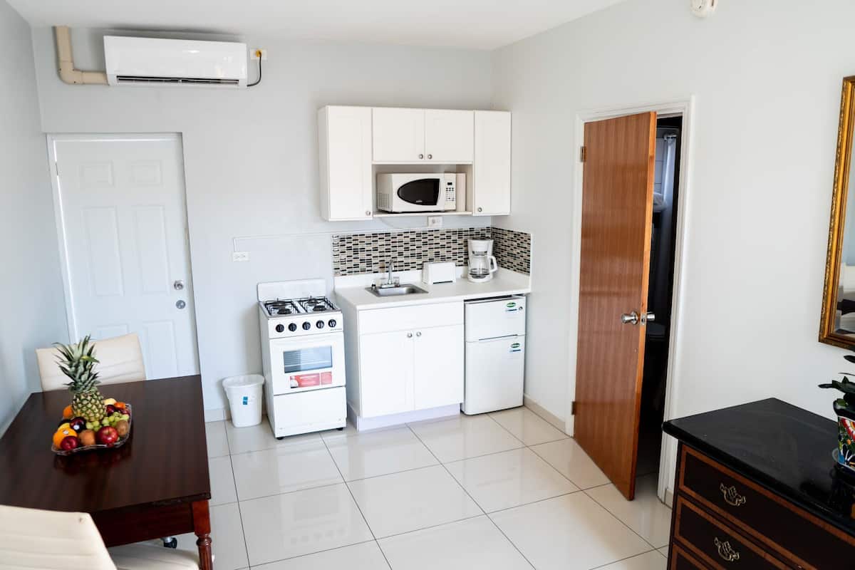 A compact kitchen with a gas stove, microwave, white cabinets, and a coffee maker.