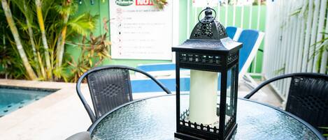 Una mesa de vidrio con un farol negro en el centro, rodeada de sillas de mimbre.