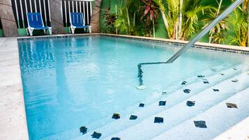 Relax by the pool surrounded by lush greenery and comfortable lounge chairs.