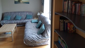 A living room with a grey sofa, a wooden coffee table, and a bookshelf filled with books. - Gîte Pour 8-10 Personnes Avec vue Imprenable ! (Gérardmer)