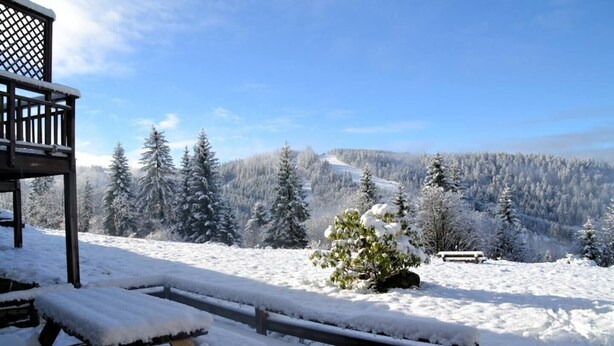 A wooden deck with a picnic table and benches, overlooking a snowy landscape with trees and a distant path. - Gîte Pour 8-10 Personnes Avec vue Imprenable ! (Gérardmer)
