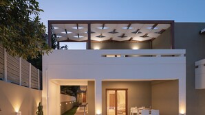 A modern two-story house with a covered patio, outdoor seating, and a staircase leading to the upper level. - De.Light Boutique Villa II, close to Rethymno (Atsipopoulo)
