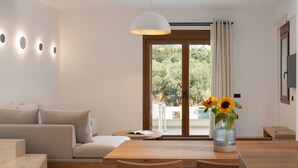 A modern living room with a sofa, wooden coffee table, and a vase with sunflowers. - De.Light Boutique Villa II, close to Rethymno (Atsipopoulo)
