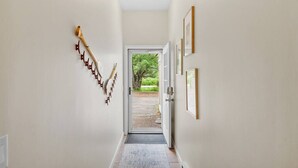 Un pasillo con un adorno de pared de madera, una puerta que da al exterior y cuadros enmarcados.