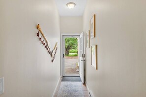 A hallway with a wooden wall decoration, a door leading outside, and framed pictures on the wall.
