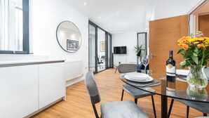 Un comedor moderno con una mesa de vidrio, sillas grises y piso de madera.