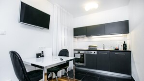 Moderni keittiö, jossa on mustat kaapit, valkoinen työtaso ja sisäänrakennettu uuni.