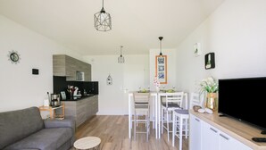 Un salon moderne avec un canapé gris, une table basse en bois et un téléviseur posé sur un meuble en bois.
