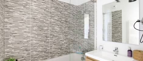 A modern bathroom with a glass-enclosed shower, a white sink, and a wooden vanity.