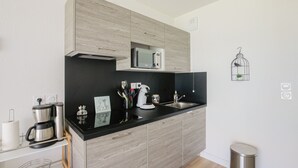 Une cuisine moderne avec un plan de travail noir, des appareils en acier inoxydable et des armoires en bois.