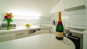 Een moderne keuken met een wit aanrecht, een bloemenvaas, een fles champagne en twee glaasjes.