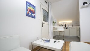 Een knus verblijf met een kitchenette, een eethoek en een klein tafeltje met boeken en afstandsbedieningen.