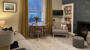 Un salon comprenant un coin repas, une bibliothèque, une cheminée et un téléviseur.