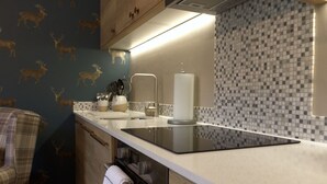 Une cuisine moderne avec un plan de travail noir, un évier et une cuisinière. On y trouve des placards et un porte-serviettes.