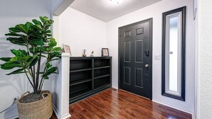 A hallway with a potted plant, a black bookshelf, and a dark door. - Mountain Bikers Retreat (Bella Vista)