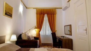 Een hotelkamer met een groot bed, een bureau, een stoel, een lamp en een raam met gordijnen.