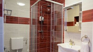 Een moderne badkamer met een douche met glazen wand, toilet en wastafel met handdoekhouder.