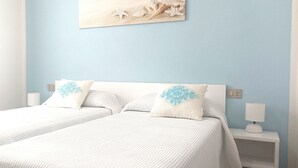 A double bed with white bedding and two decorative pillows, a bedside table with a lamp, and a wall-mounted artwork depicting sea shells and starfish. - Casa Maria (Tanaunella)