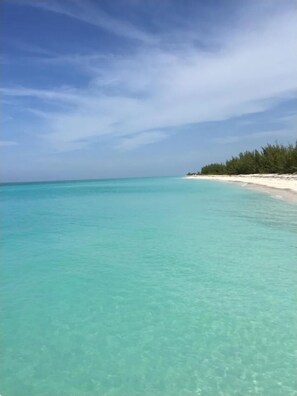 Ein Strand mit klarem türkisblauem Wasser und sandigem Ufer.