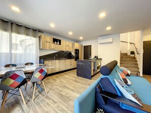 Une cuisine moderne avec des meubles en bois, un îlot en marbre et un coin repas comprenant une table et des chaises.