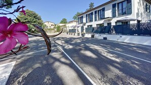 A street view with a building featuring a white facade, multiple windows, and a balcony. - Villas A du Golf Mougins (Mougins)