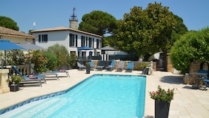 A swimming pool with lounge chairs and umbrellas, surrounded by a stone patio and lush greenery. - Villas A du Golf Mougins (Mougins)