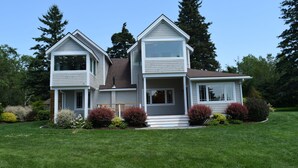 Une maison à deux étages avec un porche à l’avant, un garage et une pelouse bien entretenue.
