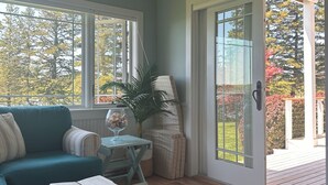 Un salon chaleureux avec un canapé de couleur turquoise, une table basse en bois et une vue sur une terrasse accessible par une porte vitrée.