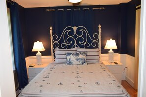 Un lit bien fait, avec une couvre-lit à motifs, deux lampes de chevet et une tête de lit décorative.