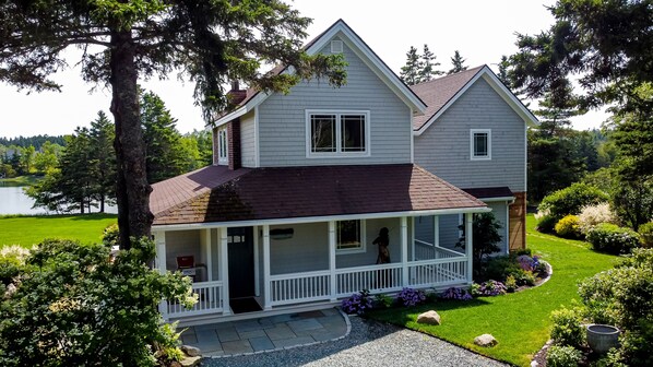 Une maison à deux étages avec un porche, une cheminée et une pelouse bien entretenue.