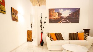 A living room with a white sofa, a round coffee table, a painting on the wall, and a wooden cabinet. - Casa Opera lovely apartment in Rome (Roma)