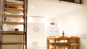 A loft-style room with a wooden staircase, a dining area with a table and chairs, and a kitchen area with a refrigerator and microwave. - Casa Opera lovely apartment in Rome (Roma)