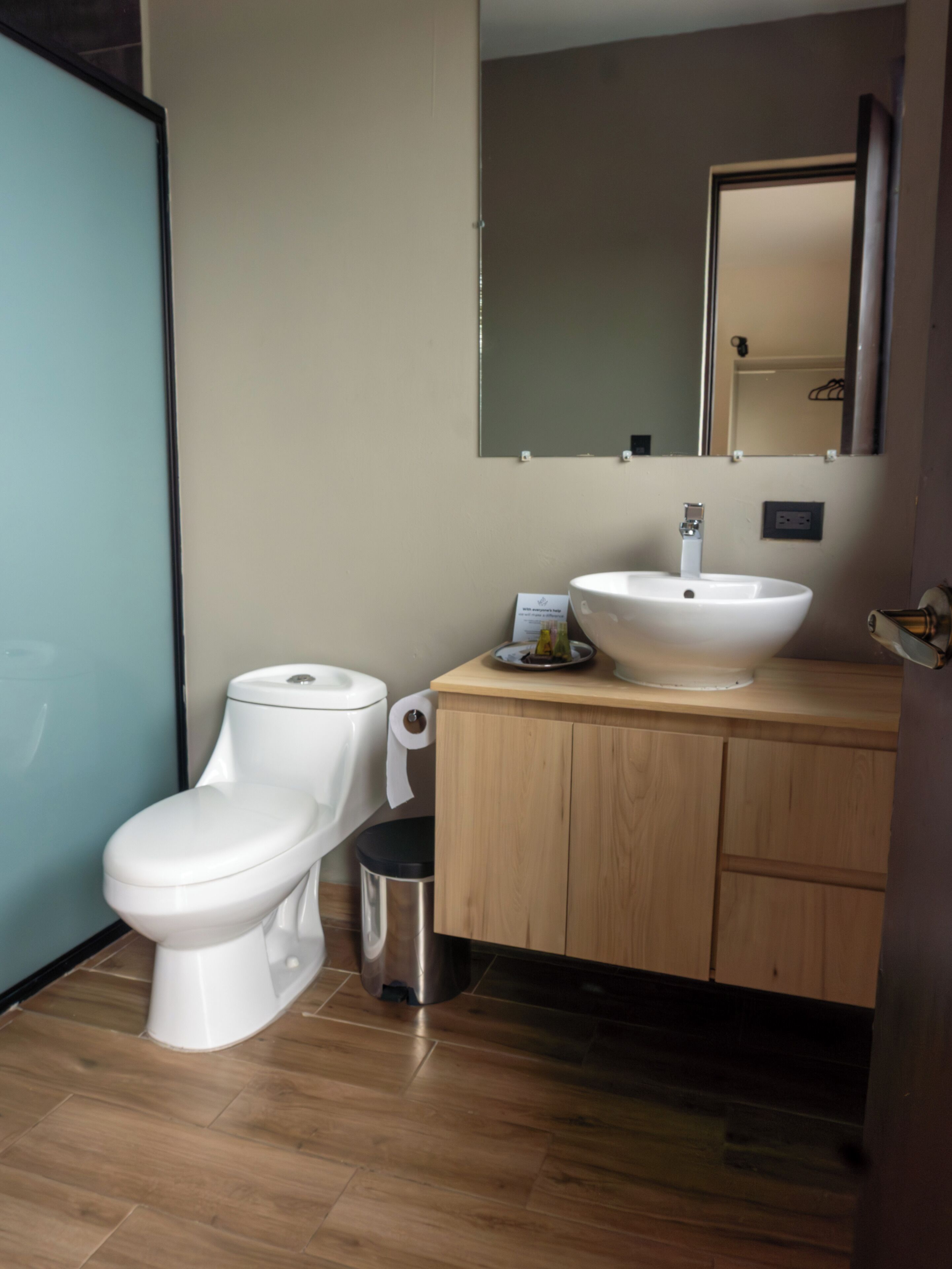 Une salle de bain équipée de toilettes, d’un lavabo, d’un miroir et de meubles en bois.