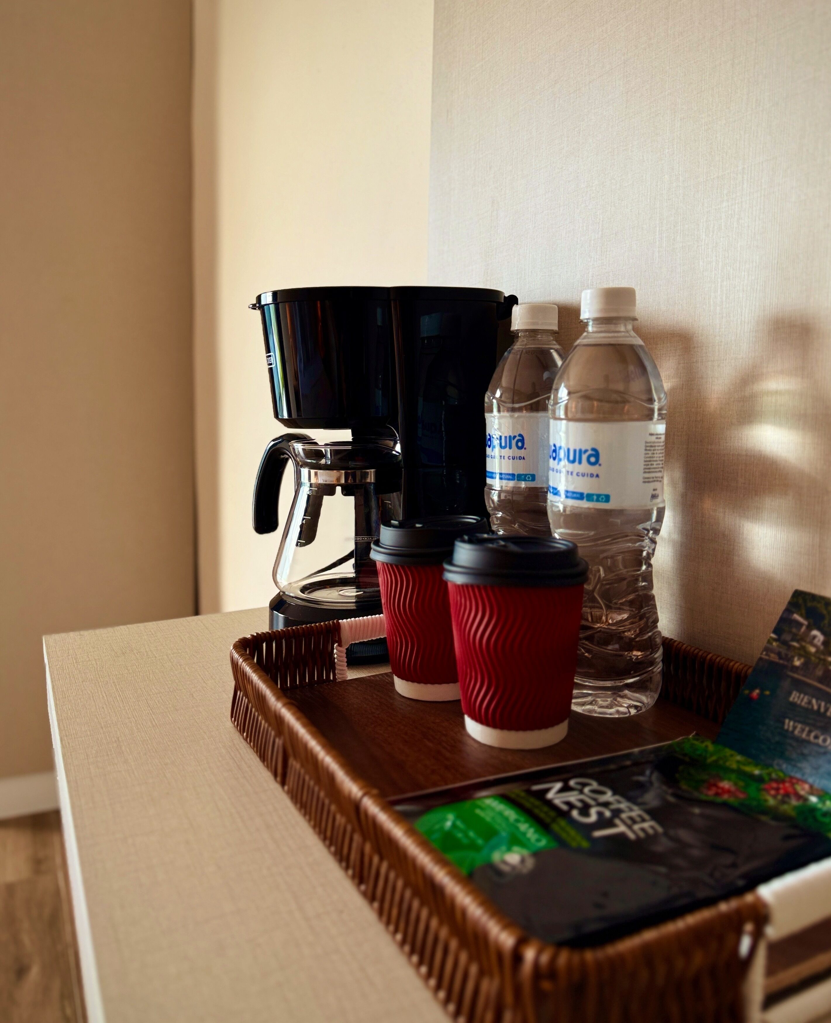 Une machine à café, deux bouteilles d’eau et un plateau avec un livre, le tout posé sur une table.